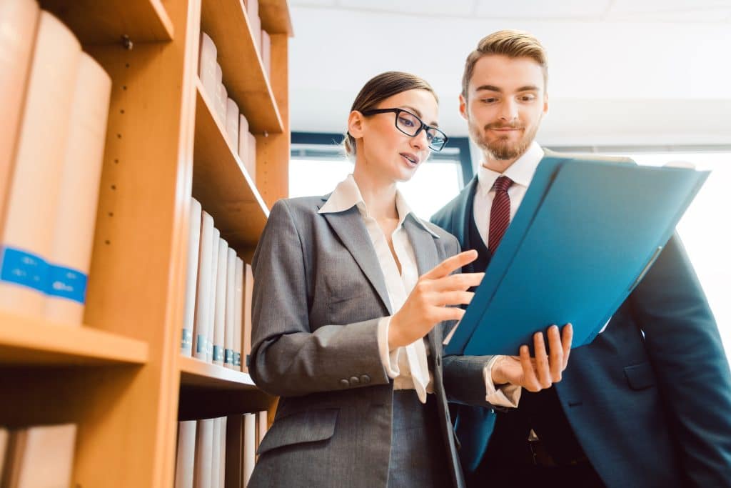 Lawyers in library of law firm discussing strategy in a case holding file