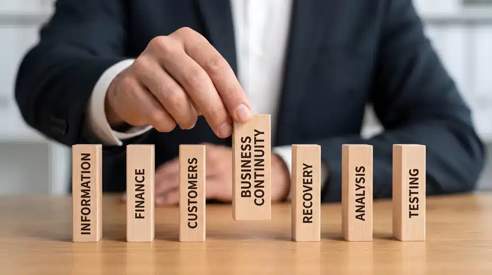 Business Continuity with VoIP: Staying Connected During Outages 1 Person arranging wooden blocks representing business continuity and recovery